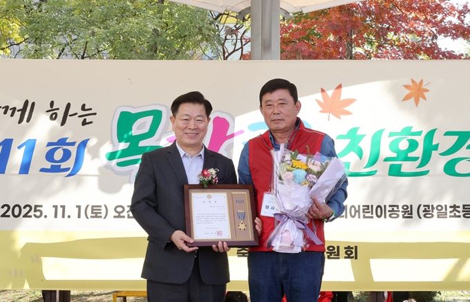 박승원 광명시장이 지난 1일 우리어린이공원에서 열린 ‘제11회 가족과 함께하는 목감천 친환경 축제’에 참석해 광명6동 주민자치회 위원에게 시장표창을 수여하고 기념사진을 촬영하고 있다.