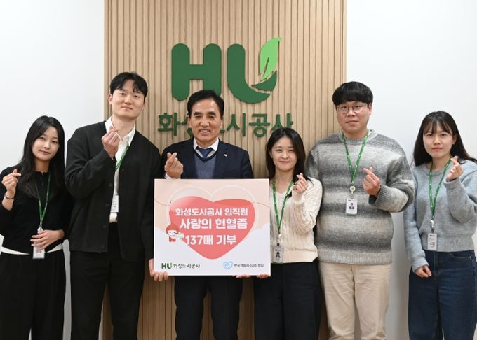 화성도시공사 한병홍 사장이 임직원들이 자발적으로 기부한 헌혈증 전달을 알리는 판넬을 들고 기념촬영을 하고 있다.